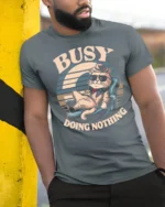 Lazy Cool Cat Busy Doing Nothing Retro Sunset Tshirt - model wearing grey tee, leaning on column