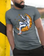 Celestial Dreamer Astronaut Reclining On Moon Graphic Tshirt - model wearing grey tee, leaning on column
