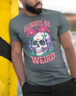Whimsical Always Be Weird Floral Skull Graphic Tshirt - model wearing grey tee, leaning on column
