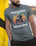 Funny Fitness Skeleton Taco In My Mouth Sunset Graphic Tee - model wearing grey tee, leaning on column