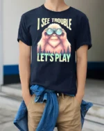 Bigfoot Wilderness Scout Binoculars Adventure Graphic Tshirt - model wearing navy tee with hands in pockets