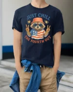 Funny Raccoon Just Chill The Fourth Out Independence Day Tee - model wearing navy tee with hands in pockets