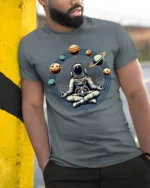 Astronaut Meditation Space Planets Zen Cosmic Graphic Tee Tshirt - model wearing grey tee, leaning on column