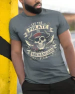 Let The Pirate Shenanigans Begin Skull Graphic Tee Tshirt - model wearing grey tee, leaning on column