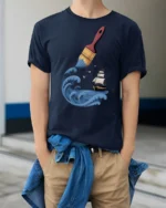 Creative Ocean Paint Brush Wave Ship Artistic Graphic T Shirt - model wearing navy tee with hands in pockets