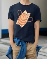 Cute Orange Tabby Cat in Paper Bag Graphic Tshirt - model wearing navy tee with hands in pockets