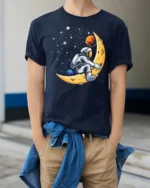Creative Astronaut Riding Crescent Moon Space Graphic Tee - model wearing navy tee with hands in pockets