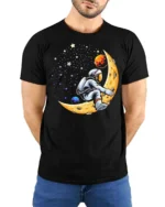 Creative Astronaut Riding Crescent Moon Space Graphic Tee - model wearing black tee with hands behind back