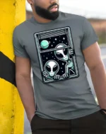 Intriguing Extraterrestrial Window Peeking Space Graphic Tee - model wearing grey tee, leaning on column