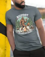 Funny Bigfoot Grabbed My Wiener Campfire Cookout Tshirt - model wearing grey tee, leaning on column