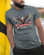Proud Home Of The Brave United States National Slogan Tee - model wearing grey tee, leaning on column