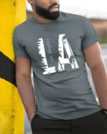 Coastal Urban Skyline Palm Tree Monochromatic Graphic Tee - model wearing grey tee, leaning on column