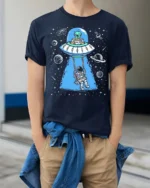 Creative Alien Spaceship Astronaut Swing Cosmic Graphic Tee - model wearing navy tee with hands in pockets