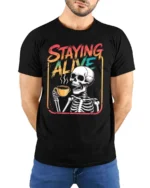 Staying Alive Skeleton Coffee Drinking Graphic Tee - model wearing black tee with hands behind back