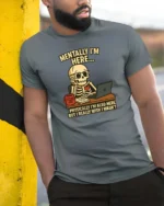 Relatable Mentally I’m Here Office Desk Skull Graphic Tee - model wearing grey tee, leaning on column