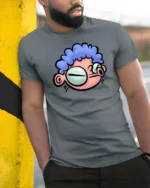 Quirky Big Eyed Blue Curly Hair Cartoon Character Graphic Tee - model wearing grey tee, leaning on column