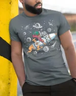 Playful Interstellar Rocket Rider Alien Spaceman Tshirt - model wearing grey tee, leaning on column