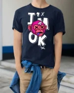 Gritty Pink Monkey Im Ok Broken Cartoon Graphic Tshirt - model wearing navy tee with hands in pockets