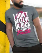 Motivating I Don’t Believe In Luck Keep The Faith Tshirt - model wearing grey tee, leaning on column
