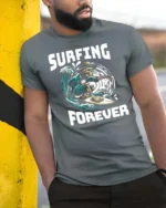 Adventurous Surfing Forever Skeleton Wave Rider Graphic Tee - model wearing grey tee, leaning on column