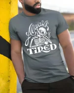 Sarcastic Always Tired Skeleton Drinking Coffee Graphic Tee - model wearing grey tee, leaning on column
