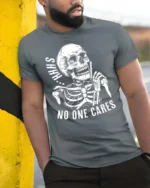 Sarcastic Shhh No One Cares Silent Skull Graphic Tshirt - model wearing grey tee, leaning on column