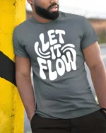 Groovy Let It Flow White Bubble Text Retro Graphic Tee - model wearing grey tee, leaning on column