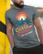 Inspiring Chase The Sunset Outdoor Nature Graphic Tee - model wearing grey tee, leaning on column